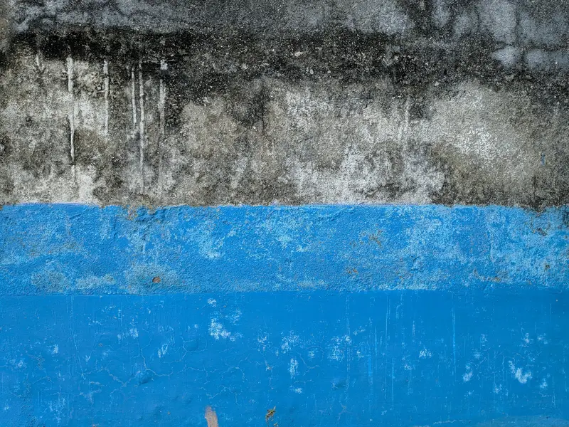 Concrete block basement wall with old paint and damp staining before an interior drainage system
