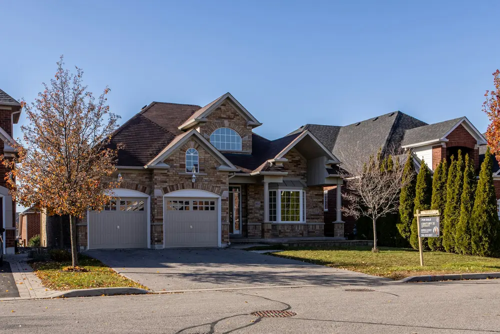 Row of stone and brick two-storey houses with double garages on a suburban street