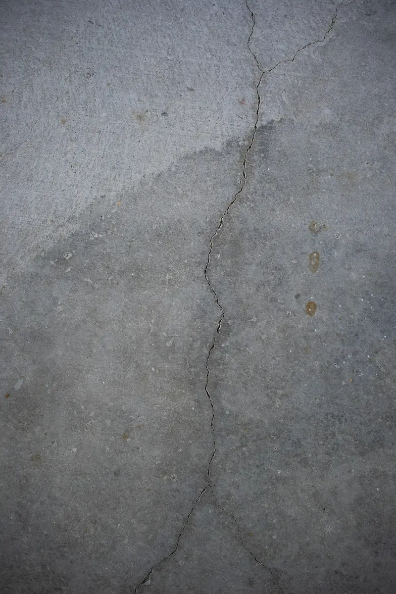 Fine crack running across a grey concrete basement floor