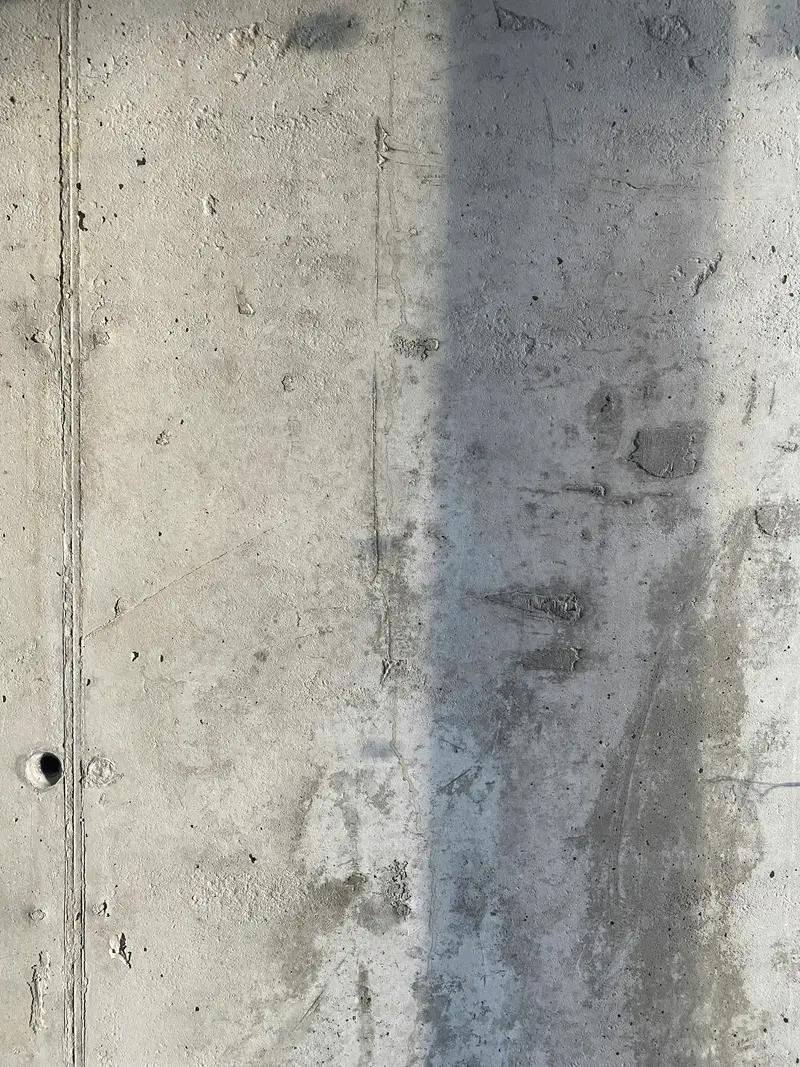 Dark damp streak running down a grey concrete wall
